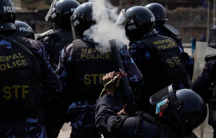 A Nepalese policeman fires tear gas as Nepalese protesters opposing a proposed U.S. half-billion dollars grant for Nepal clash with police outside the parliament in Kathmandu, Nepal, Thursday, Feb. 24, 2022. Hundreds of protesters against the US grant gathered outside the parliament clashed with riot police, who have lined up and set up barricades as lawmakers were scheduled to begin debate on the grant proposal Thursday. (AP Photo/Niranjan Shrestha)